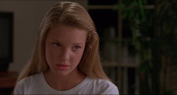 Movie still from “My Father the Hero” (1994), directed by Steve Miner – A young girl with long blonde hair wearing a white t - shirt; Close Up shot, Over the shoulder angle