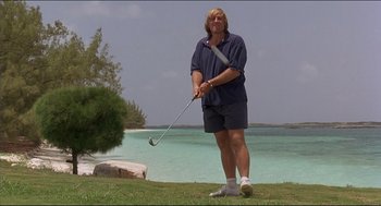 Movie still from “My Father the Hero” (1994), directed by Steve Miner – A man holding a golf club on a golf course near the ocean; Wide shot, Low angle