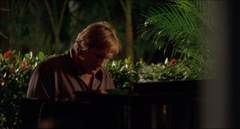 Movie still from “My Father the Hero” (1994), directed by Steve Miner – A man sitting at a table in the dark looking down; Close Up shot, Low angle