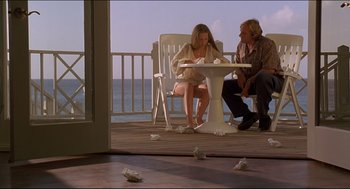 Movie still from “My Father the Hero” (1994), directed by Steve Miner – A man and a woman sitting at a table on a deck; Wide shot, High angle