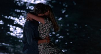 Movie still from “My Father the Hero” (1994), directed by Steve Miner – A man and a woman hugging in a dark forest; Medium shot, High angle