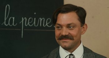 Movie still from “My Father's Glory” (1990), directed by Yves Robert – A man in a suit and tie with a mustache; Close Up shot, Low angle