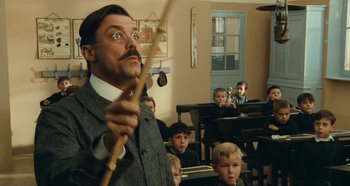 Movie still from “My Father's Glory” (1990), directed by Yves Robert – A man holding a stick in front of a group of children; Medium shot, Low angle