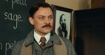 Movie still from “My Father's Glory” (1990), directed by Yves Robert – A man with a mustache standing in front of a picture of a man; Close Up shot, Low angle