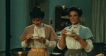 Movie still from “My Father's Glory” (1990), directed by Yves Robert – A couple of women standing next to each other holding cups; Medium shot, Low angle