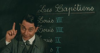 Movie still from “My Father's Glory” (1990), directed by Yves Robert – A man standing in front of a blackboard with a chalkboard with roman numerals written on it; Close Up shot, Over the shoulder angle