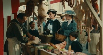 Movie still from “My Father's Glory” (1990), directed by Yves Robert – A group of people standing around a table with food; Medium shot, High angle