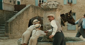 Movie still from “My Father's Glory” (1990), directed by Yves Robert – A group of people standing next to each other near a fountain; Wide shot, High angle