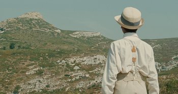 Movie still from “My Father's Glory” (1990), directed by Yves Robert – A man wearing a hat standing on top of a hill; Medium shot, Low angle