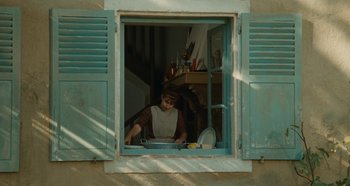 Movie still from “My Father's Glory” (1990), directed by Yves Robert – A woman in an open window looking out of a window; Wide shot, Low angle