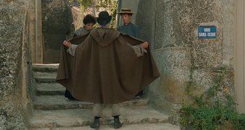 Movie still from “My Father's Glory” (1990), directed by Yves Robert – Two men wearing hats and a brown cape; Wide shot, Over the shoulder angle
