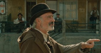 Movie still from “My Father's Glory” (1990), directed by Yves Robert – An older man wearing a black hat and smiling; Medium shot, Over the shoulder angle
