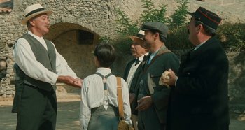 Movie still from “My Father's Glory” (1990), directed by Yves Robert – A group of men standing next to each other on a street; Medium shot, Over the shoulder angle
