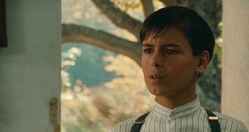 Movie still from “My Father's Glory” (1990), directed by Yves Robert – A young man in a white shirt is looking at the camera; Close Up shot, Low angle