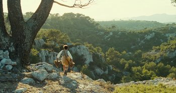 Movie still from “My Father's Glory” (1990), directed by Yves Robert – A man walking up a hill with two bags; Extreme Wide shot, Low angle