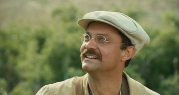Movie still from “My Father's Glory” (1990), directed by Yves Robert – A man with a mustache wearing glasses and a hat; Close Up shot, Low angle