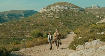 A man and a woman walking on a dirt road