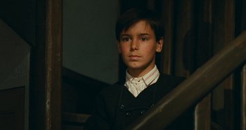 Movie still from “My Father's Glory” (1990), directed by Yves Robert – A young man wearing a suit and a white shirt; Close Up shot, High angle