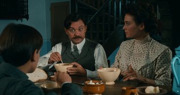 Movie still from “My Father's Glory” (1990), directed by Yves Robert – A group of people sitting at a table eating food; Medium shot, Over the shoulder angle