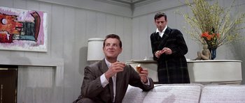 Movie still from “My Geisha” (1962), directed by Jack Cardiff – A man in a suit eating a donut while another man in a suit looks on; Medium shot, Low angle