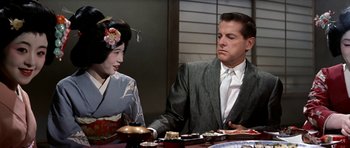 Movie still from “My Geisha” (1962), directed by Jack Cardiff – A man and a geisha sitting at a dinner table; Medium shot, Over the shoulder angle
