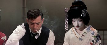 Movie still from “My Geisha” (1962), directed by Jack Cardiff – A man and a woman smoking in front of a wall; Close Up shot, Over the shoulder angle