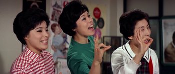 Movie still from “My Geisha” (1962), directed by Jack Cardiff – A young woman smiling and making a funny face; Medium shot, High angle