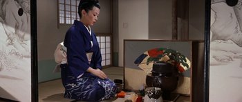 Movie still from “My Geisha” (1962), directed by Jack Cardiff – A woman sitting on the floor in front of a painting; Medium shot, High angle