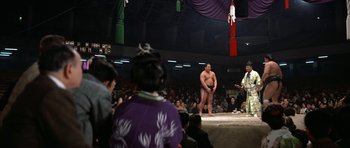 Movie still from “My Geisha” (1962), directed by Jack Cardiff – A sumo wrestling match in progress in front of an audience; Wide shot, Low angle