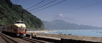 Movie still from “My Geisha” (1962), directed by Jack Cardiff – A train traveling on the tracks near a body of water; Extreme Wide shot, Low angle