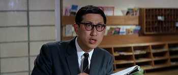 Movie still from “My Geisha” (1962), directed by Jack Cardiff – A man wearing a suit and glasses is looking at the camera; Close Up shot, Low angle