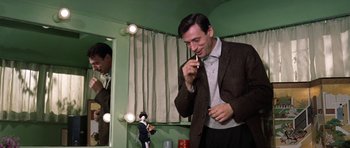 Movie still from “My Geisha” (1962), directed by Jack Cardiff – A man talking on a cell phone in front of a mirror; Medium shot, Low angle