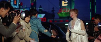 Movie still from “My Geisha” (1962), directed by Jack Cardiff – A group of people standing next to each other near a car; Medium shot, Over the shoulder angle