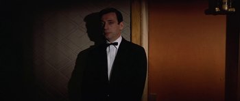 Movie still from “My Geisha” (1962), directed by Jack Cardiff – A man in a tuxedo standing next to a wall; Medium shot, Low angle