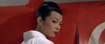 Movie still from “My Geisha” (1962), directed by Jack Cardiff – A woman with red lipstick is sitting on a red chair; Close Up shot, Low angle