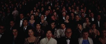 Movie still from “My Geisha” (1962), directed by Jack Cardiff – A large group of people sitting in a dark room; Wide shot, High angle