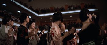 Movie still from “My Geisha” (1962), directed by Jack Cardiff – A group of people standing in front of an audience clapping; Medium shot, Low angle
