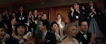 Movie still from “My Geisha” (1962), directed by Jack Cardiff – A group of people sitting and standing in a room; Medium shot, Low angle