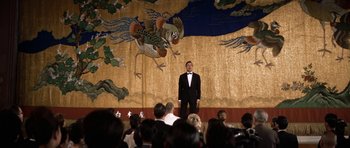Movie still from “My Geisha” (1962), directed by Jack Cardiff – A man standing on a stage in front of an audience; Wide shot, Low angle