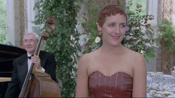 Movie still from “My Left Foot” (1989), directed by Jim Sheridan – A woman with short red hair is smiling at the camera; Medium shot, Over the shoulder angle