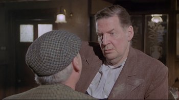Movie still from “My Left Foot” (1989), directed by Jim Sheridan – An older man wearing a hat and a jacket talking to a younger man; Close Up shot, Over the shoulder angle
