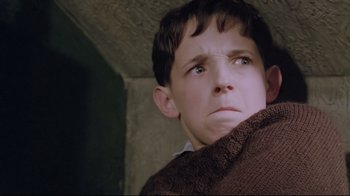 Movie still from “My Left Foot” (1989), directed by Jim Sheridan – A young boy wearing a brown sweater looking at the camera; Close Up shot, Low angle