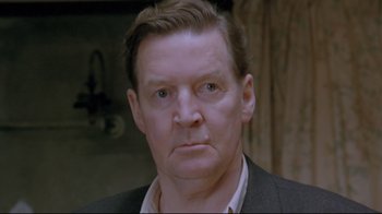 Movie still from “My Left Foot” (1989), directed by Jim Sheridan – A person wearing a suit and tie; Close Up shot, Low angle