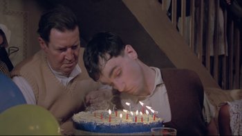 Movie still from “My Left Foot” (1989), directed by Jim Sheridan – A man blowing out candles on a birthday cake; Close Up shot, High angle