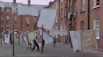 Movie still from “My Left Foot” (1989), directed by Jim Sheridan – A group of people hanging clothes on a clothesline; Wide shot, High angle