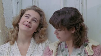 Movie still from “My Left Foot” (1989), directed by Jim Sheridan – Two young women sitting next to each other on a wall; Close Up shot, High angle
