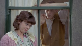 Movie still from “My Left Foot” (1989), directed by Jim Sheridan – A man and a woman looking out of a window; Medium shot, Over the shoulder angle