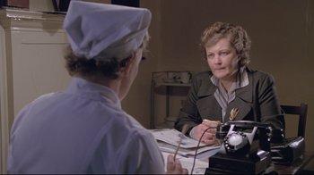 Movie still from “My Left Foot” (1989), directed by Jim Sheridan – A woman sitting at a table talking to a nurse; Medium shot, High angle