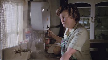 Movie still from “My Left Foot” (1989), directed by Jim Sheridan – An older woman in an apron is working in a kitchen; Medium shot, High angle