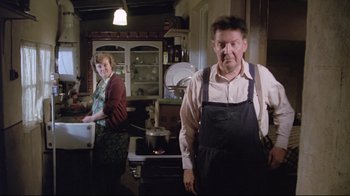 Movie still from “My Left Foot” (1989), directed by Jim Sheridan – A man and a woman standing in a kitchen next to an oven; Medium shot, Low angle